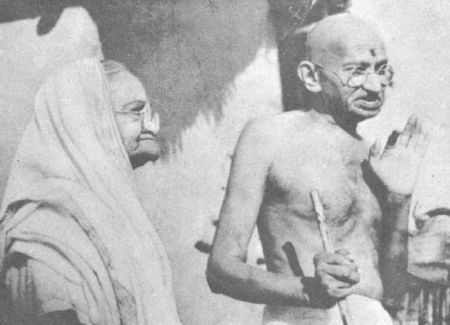Kasturba Gandhi standing beside Mahatma Gandhi