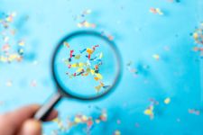 Microplastic particles magnified against a blue background